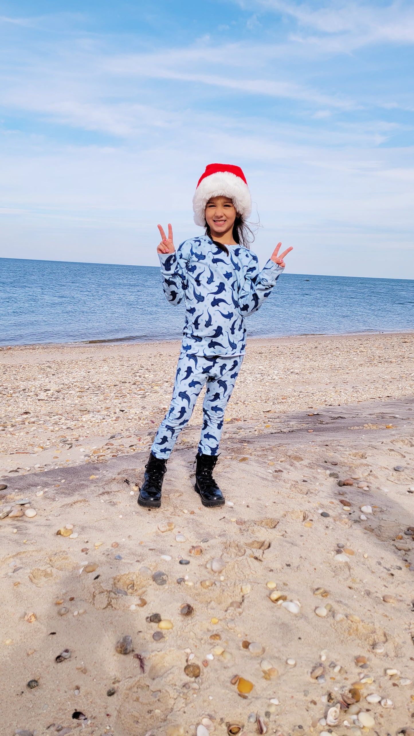 Girl in Holiday narwhal pajama set and santa hat