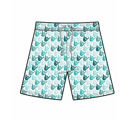 Mock up of boys white swim shorts with green and teal shaka hands