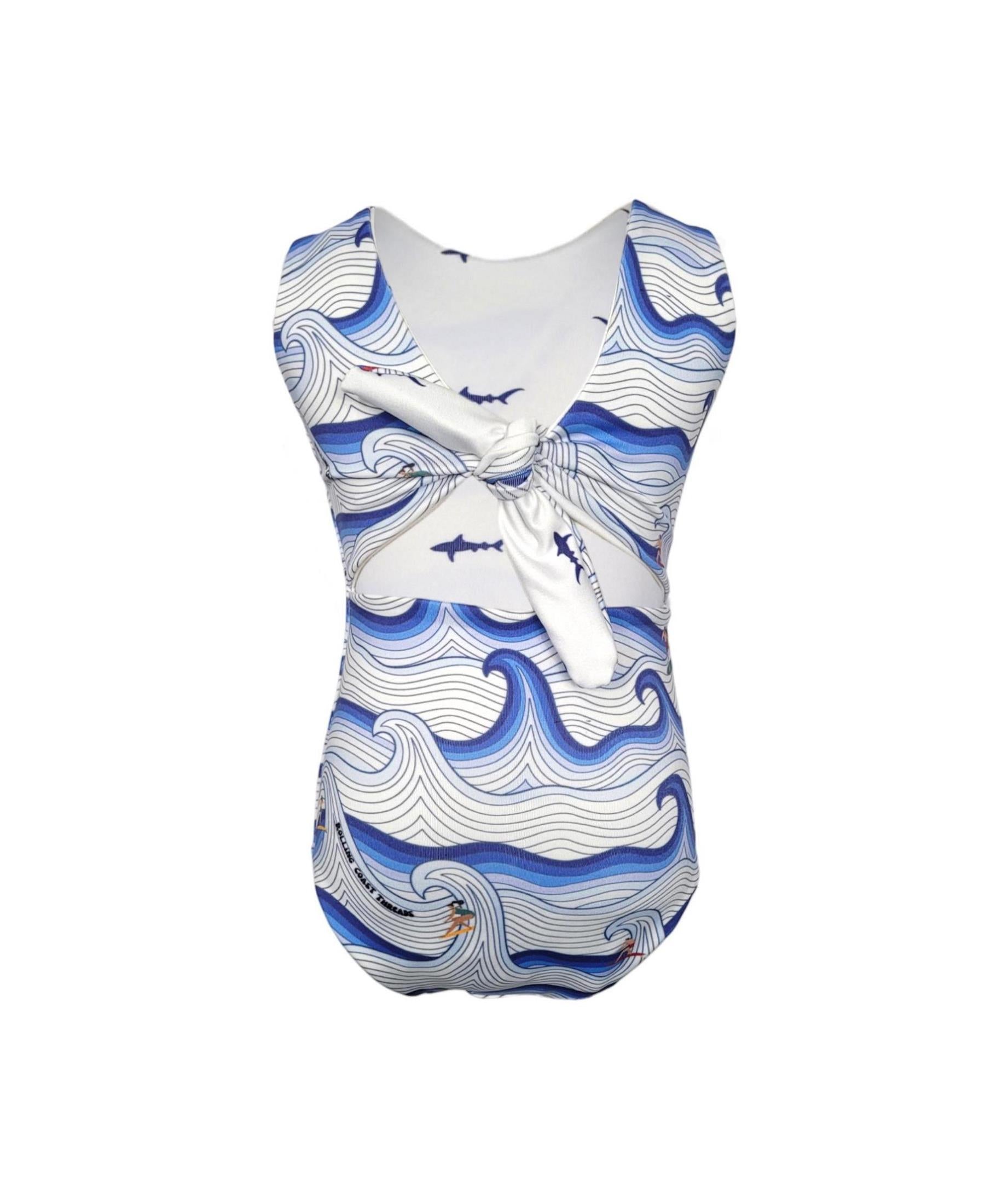 Girls reversible swimsuit. Surfers on white and blue waves.