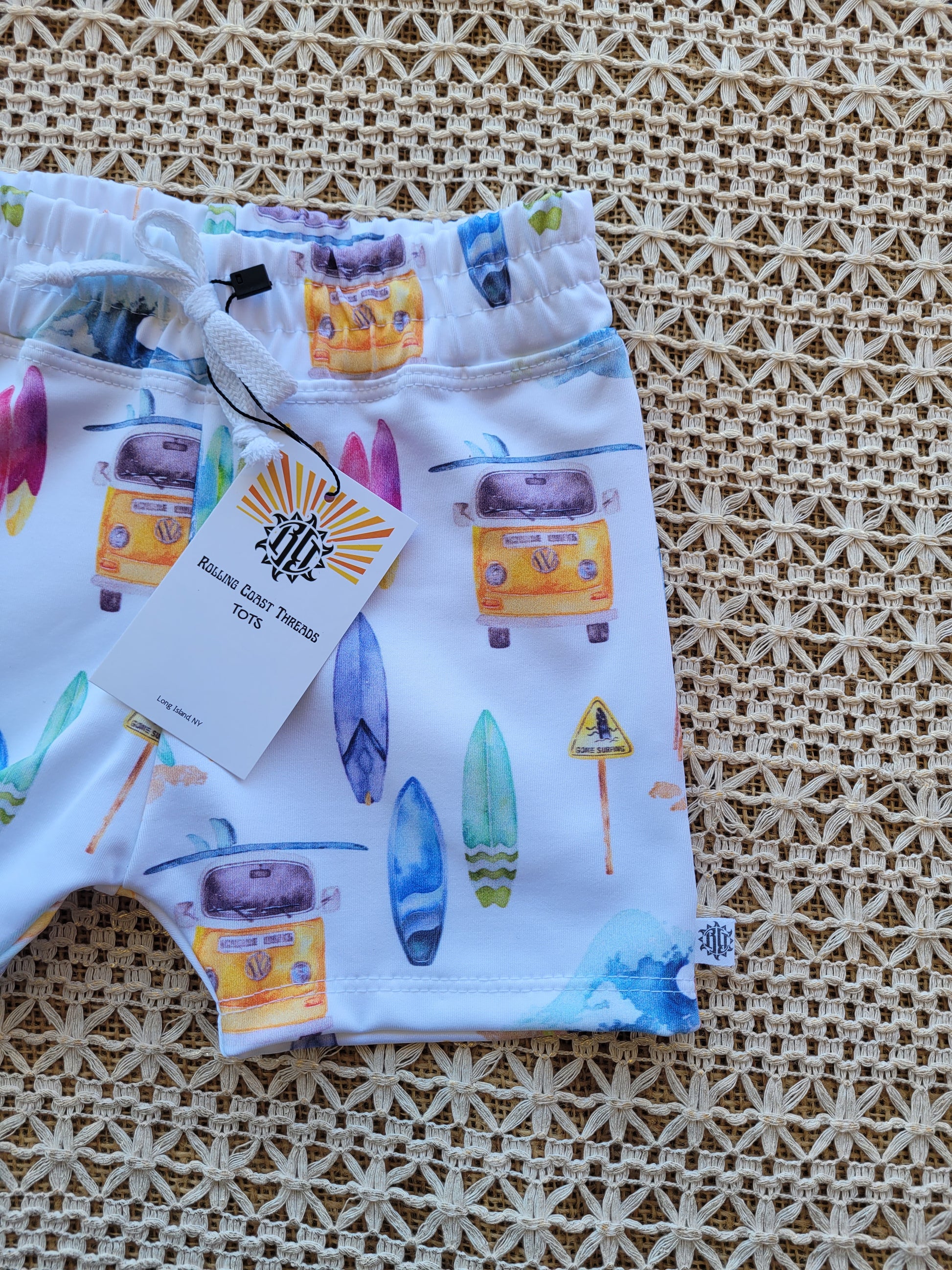 Close up of Boys white swim shorts with colorful surfboards