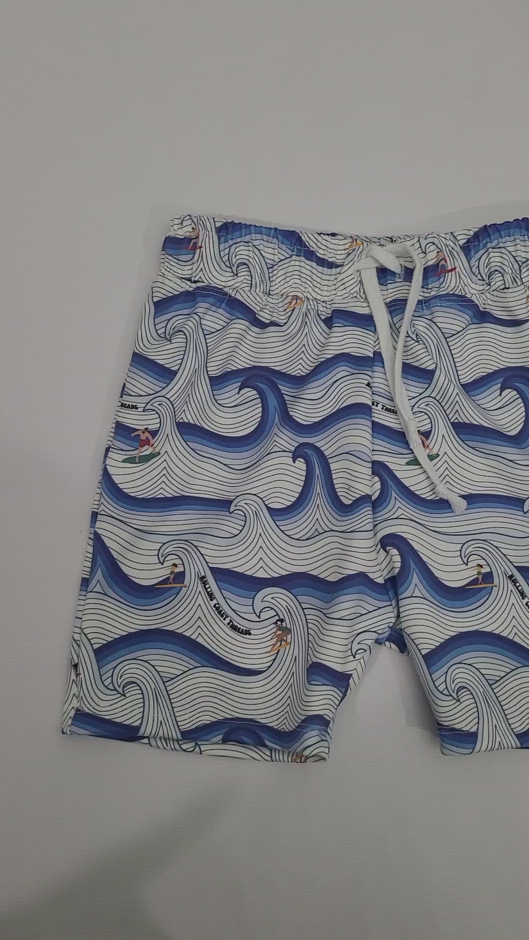Boys swim shorts. White and blue waves with surfers