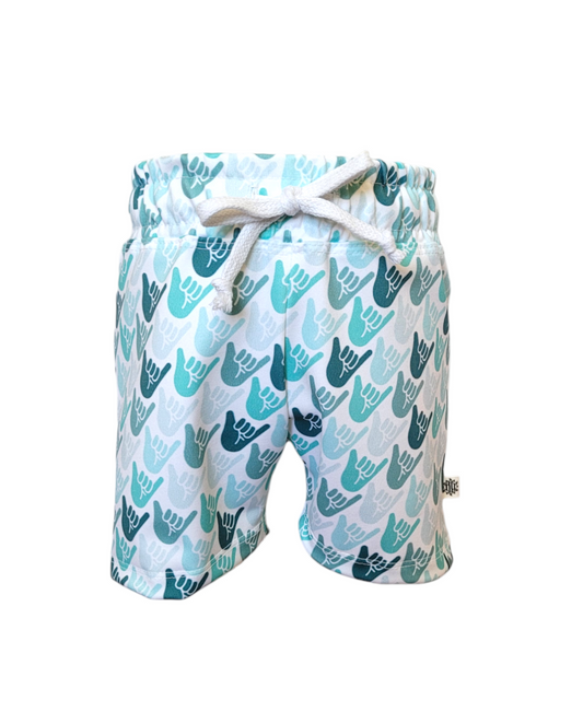 Front of boys white swim shorts with green and teal shaka hands